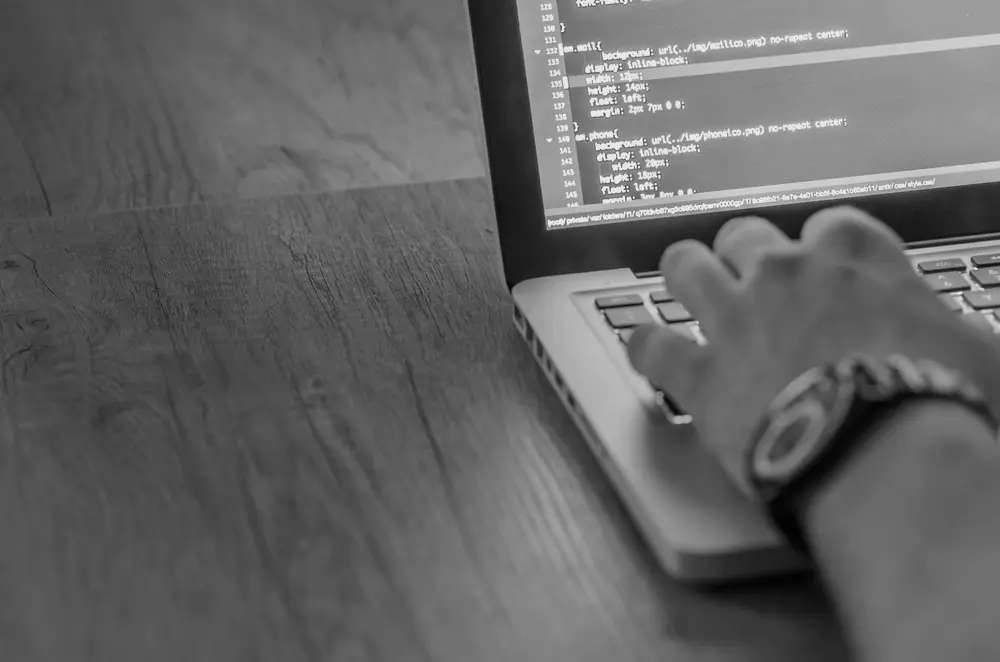 A person building a website on a laptop with code on screen